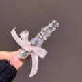 Gros plan détaillé d'une pince à cheveux poignard en strass étincelant au nœud rose. - Pince à Cheveux Strass Rose