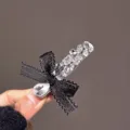 Gros plan détaillé de la élégante pince à cheveux avec nœud noir et strass brillants. - Pince à Cheveux Strass Noire