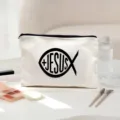 Close-up detail of white canvas cosmetic pouch featuring a black Jesus fish religious graphic design. - Religious Jesus Fish Pattern (02)