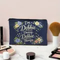 Detail view of a navy blue makeup pouch featuring cute floral prints and personalized quote. - Floral and Personalized Slogan / Dark Blue