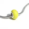 Gros plan détail d'une perle charm en pierre craquelée jaune vif sur un bracelet chaîne argent. - Jaune Citron