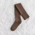 Primer plano detallado de calcetines altos de punto marrón sobre una alfombra blanca esponjosa. - Sobre la rodilla / Café