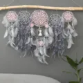 Close-up detail of handmade multi-ring dream catcher with pink lace, feathers, and wall hanging decor. - Multicolor