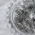 Gros plan détaillé des anneaux de saut en argent dans un bol en verre pour bijoux faits main. - K Blanc/Argent