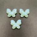 Gros plan detail de perles papillon en acrylique lumineuse avec trou vertical pour bijoux DIY. - Vert clair
