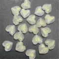 Primer plano de cuentas de corazón facetadas translúcidas con purpurina dorada DIY. - Blanco