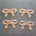 Close-up detail of translucent orange glitter star bowknot resin DIY craft bead accessories. - Orange