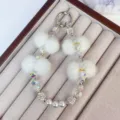 Chic plush crystal phone chain and stylish keychain featuring soft white pom poms. - White