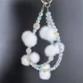 Crystal beaded phone charm with fluffy white pom poms, double strand wrist strap lanyard detail. - White