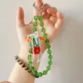Close-up detail of green and white beaded lanyard with floral charms, aesthetic bag accessory. - Green Chain