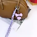 Morandi color bag pendant detail showing purple bow, heart charm and braided rope. - Purple