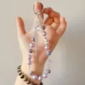 Close-up detail of purple beaded phone charm with sparkling rhinestone bow pendant and crystals. - Purple