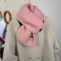 Dettaglio sciarpa di lana rosa con morbida trama a costine e caldo design autunnale. - Rosa