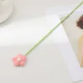 Gros plan d'une fleur rose tricotée à la main avec une longue tige verte pour la déco. - Rose