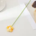 Gros plan détaillé d'une fleur bouffante en laine crochetée à la main avec tige. - Jaune Orangé