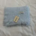 Dettaglio di sciarpa in maglia azzurra con frange morbide e accoglienti fatte a mano. - Celeste