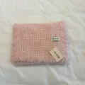 Vista dettagliata della sciarpa in maglia waffle rosa con frange ed etichetta attaccata. - Rosa