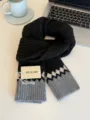 Primo piano di sciarpa in maglia nera e grigia con motivo a trecce e orlo geometrico. - Nero Grigio