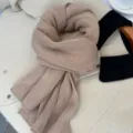 Primo piano di dettaglio di una sciarpa invernale in maglia kaki morbida con trama fine. - Kaki
