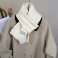 Primo piano della sciarpa in maglia bianca con bordo a contrasto nero ed etichetta. - Bianco Latte