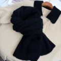 Dettaglio in primo piano di sciarpa in maglia nera, morbida e calda per la stagione invernale. - Nero
