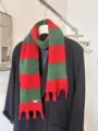 Vista dettagliata della sciarpa in maglia a blocchi di colore rosso e verde con frange. - strisce rosse e verdi