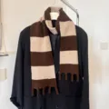 Nahaufnahme des braun-beigen gestreiften Strickschals an Mantel, gemütliches Winteraccessoire. - Khaki-Kaffee-Streifen