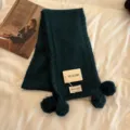 Dark green knitted scarf detail view, featuring cozy pom-pom accents and soft texture. - Dark Green
