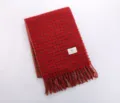 Close-up detail of the red plaid winter scarf with fringed hem and brand logo tag. - YB Red Black Fine Plaid