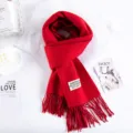 Dettaglio sciarpa rossa spessa in finto cashmere, frange morbide ed etichetta bianca, calda. - Rosso Natale Renna