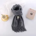 Detail view of the thick grey cashmere-like winter scarf featuring elegant tassels. - Medium Gray