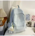 Vue détaillée d'un sac à dos bleu clair avec broderie de nœuds et pendentif en peluche. - Grand (Avec Pendentif) / Bleu