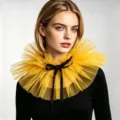 Detailaufnahme des gelben Tüll-Halskragens mit feinem Netzstoff und eleganter schwarzer Schleife. - Gold