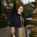 Gros plan détaillé de la cape à capuche vintage dans un décor de cour extérieure et tissu sombre. - Taille unique / Robe / Noir