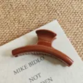 Detailed view of glossy brown hair claw clip on fabric, perfect for thick hair styling. - Large Arc / 15cm / Chocolate Brown