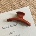 Detail view of a large brown hair claw clip on a book, showcasing the smooth glossy finish. - Medium Curved / 12cm / Chocolate Brown