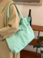 Close-up detail of the light green canvas shoulder tote bag showing casual lettering design. - Mint Green