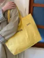 Detail shot of a casual yellow canvas tote bag with printed text, perfect for everyday use. - Yellow