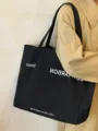 Minimalist black canvas tote bag detail view, featuring large capacity casual shoulder bag. - Black
