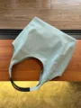 Light green denim shoulder bag detail, featuring black leather handles and casual style. - Light Blue