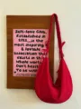 Red slouchy hobo bag detail showing the gathered scrunchie strap and soft fabric texture. - Red