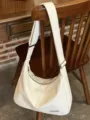 White woven shoulder bag detail, elegant leather hobo bag with wide strap and metallic accent. - White