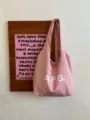 Detailed view of the pink canvas tote bag hanging on wooden board, daily casual commute style. - Pink