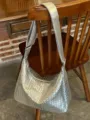 Close-up view of the silver woven shoulder bag showing the detailed leather texture and strap. - Silver