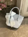 Close up detail of light blue chic handbag featuring delicate bow ribbon and bead handle. - With Silk Scarf / Blue