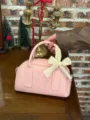 Close-up detail of the pink boston pillow bag featuring an elegant lace bow decoration. - Pink