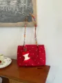 Detail view of the red floral canvas tote bag with colorful braided straps and cute apple pendant. - With Charm / S / Red