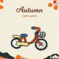 Close-up detail of cute autumn bicycle embroidered cloth patch with vibrant colored threads. - Bicycle