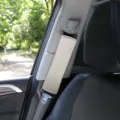Close-up detail view of a soft beige car seat belt cover installed on a vehicle seat strap. - 25*6cm / Gray