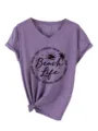 Purple V-neck short sleeve T-shirt featuring beach life graphic and knotted hem detail. - S / Purple